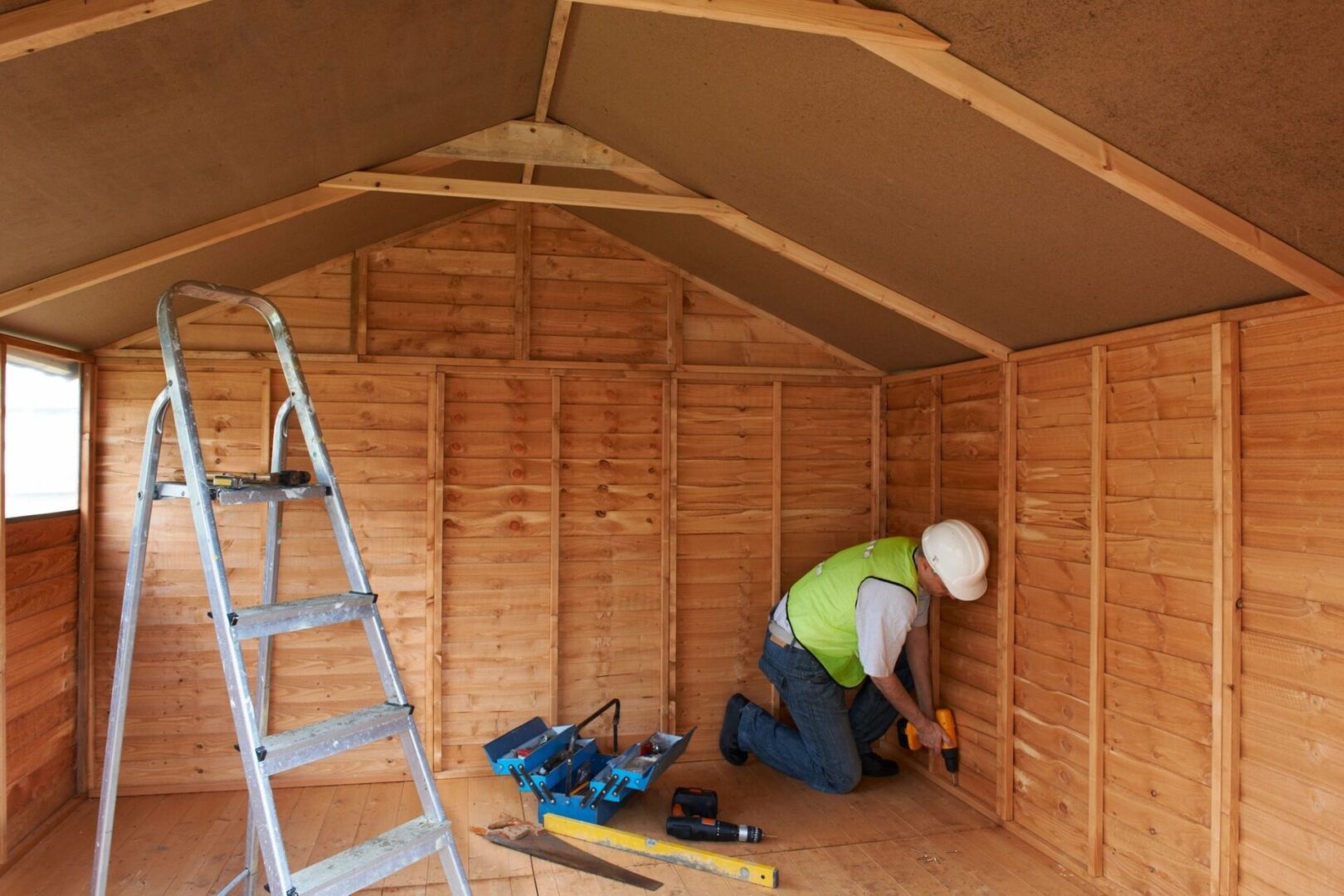 An expert in architectural design services is meticulously working on the inside of a wooden shed.